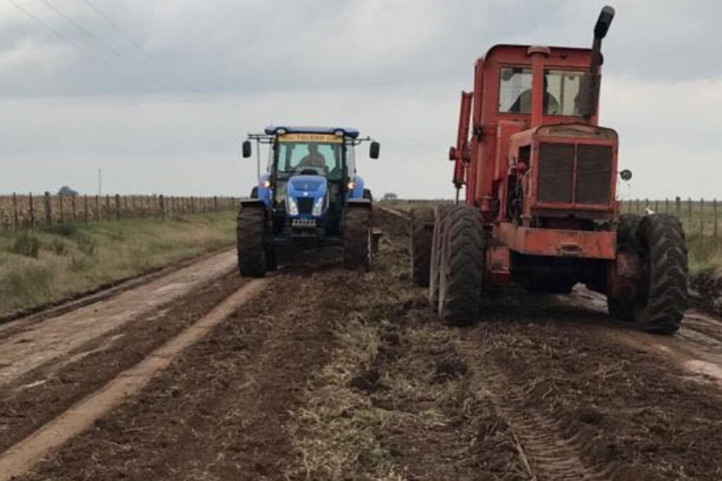 Máquina y tractor trabajando en mejoramiento de caminos rurales.