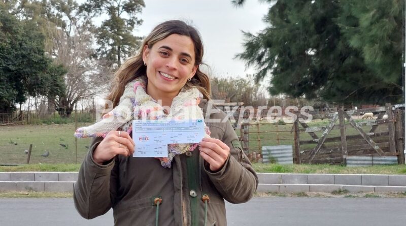 Melisa, amable cobradora de Prote Bombal, sonríe mientras muestra un bono de la rifa.