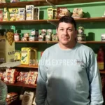 Cristian está parado entre las góndolas del negocio de Leo.